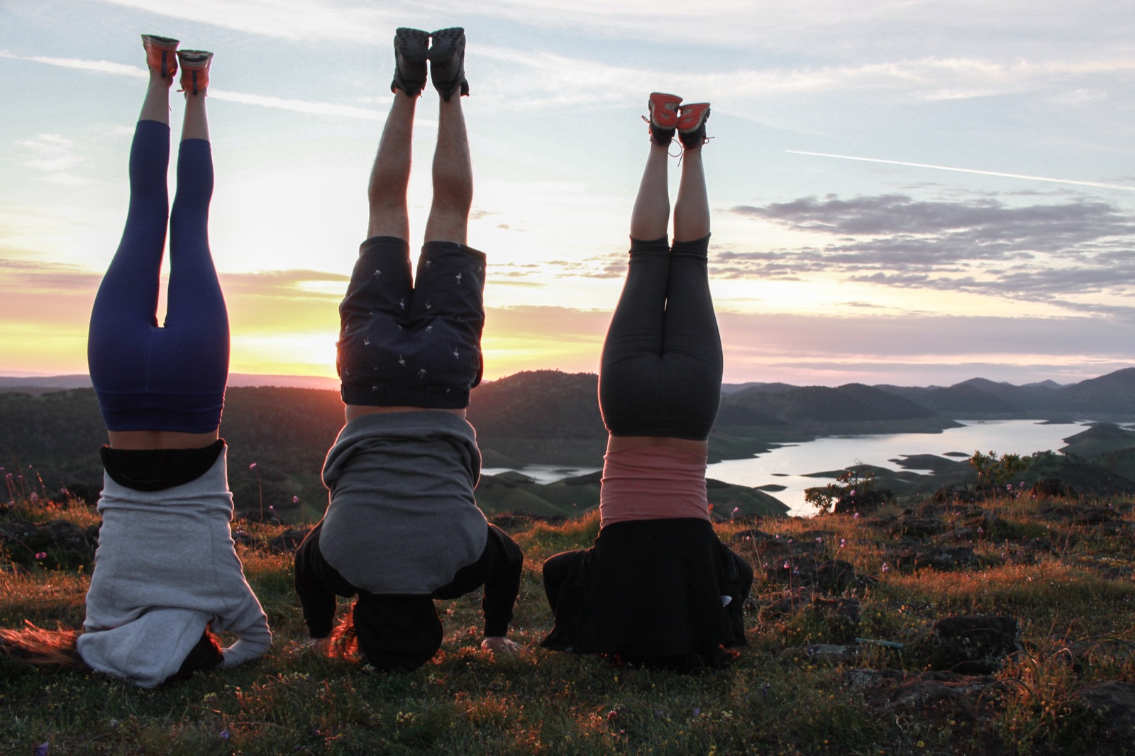 Three people in headstands at sunset